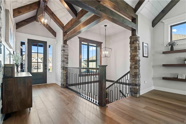 foyer with beamed ceiling, hardwood / wood-style floors, high vaulted ceiling, and an inviting chandelier