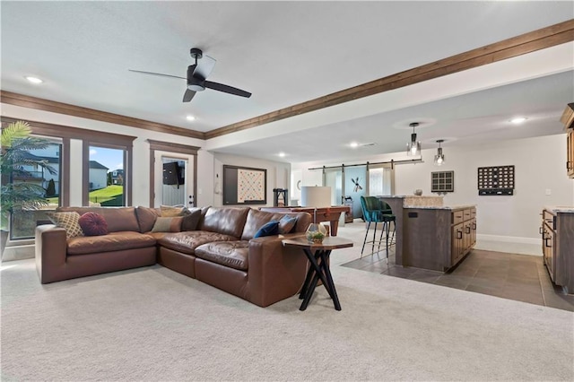 carpeted living room with ceiling fan, a barn door, and crown molding