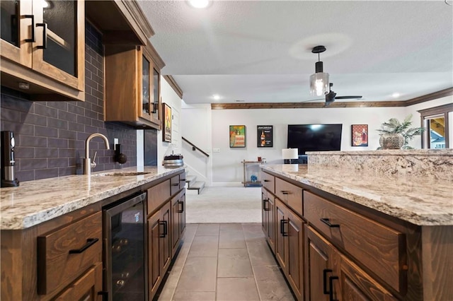 kitchen with sink, hanging light fixtures, beverage cooler, tile patterned floors, and ornamental molding