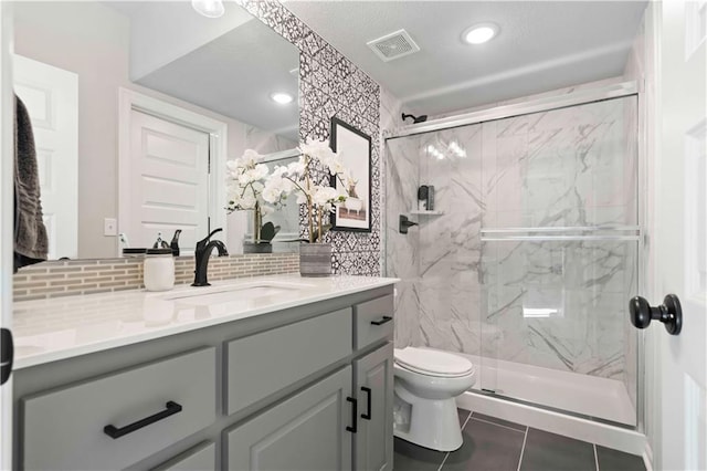 bathroom with vanity, tile patterned flooring, decorative backsplash, toilet, and walk in shower