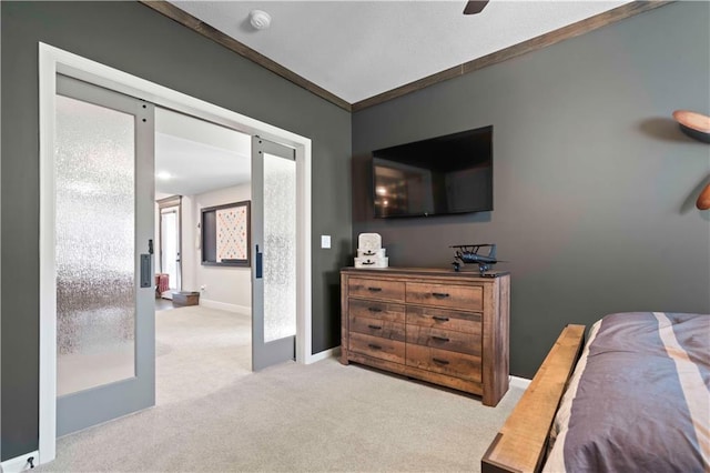 bedroom with french doors, light colored carpet, ceiling fan, crown molding, and a barn door