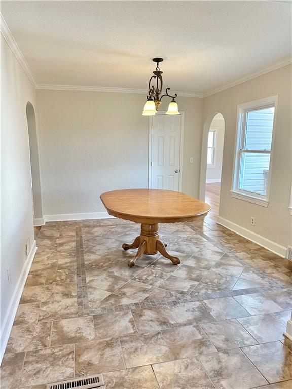 unfurnished dining area featuring crown molding and a notable chandelier