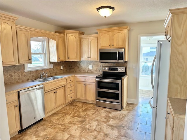 kitchen featuring light brown cabinets, sink, appliances with stainless steel finishes, and tasteful backsplash