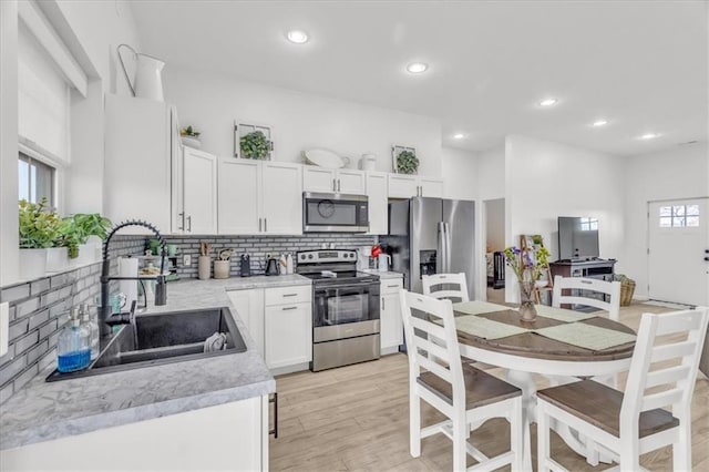 kitchen with tasteful backsplash, white cabinets, appliances with stainless steel finishes, light countertops, and a sink