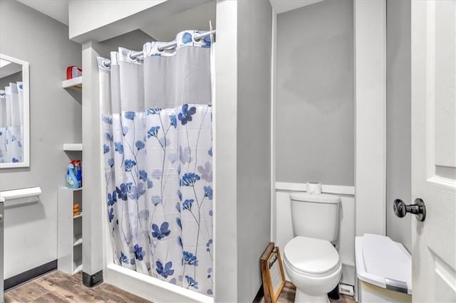 full bath featuring toilet, a stall shower, and wood finished floors