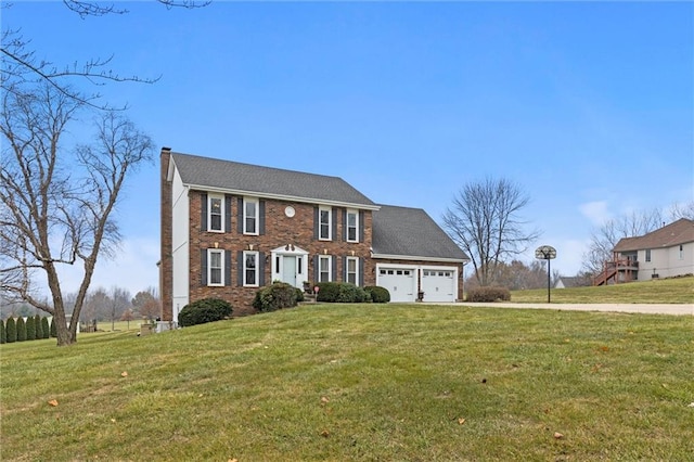 colonial-style house featuring a front yard and a garage