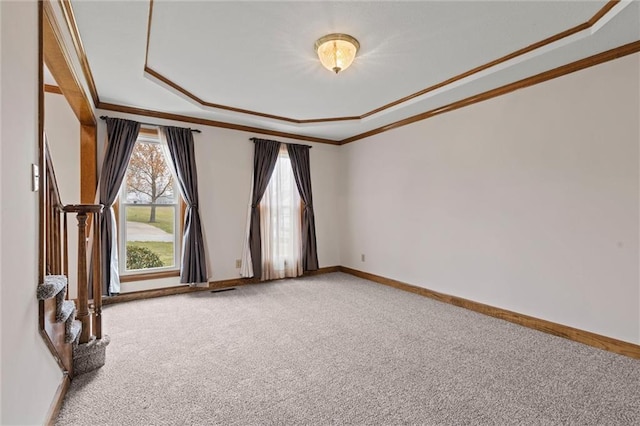 carpeted empty room with ornamental molding and a tray ceiling