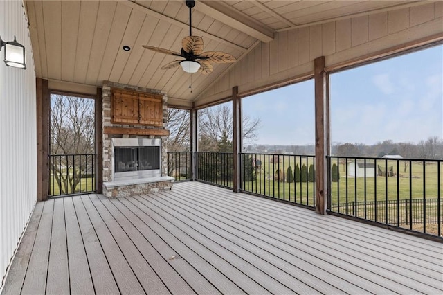 deck with ceiling fan and an outdoor stone fireplace