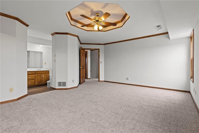 unfurnished bedroom with crown molding, carpet flooring, ceiling fan, connected bathroom, and a tray ceiling