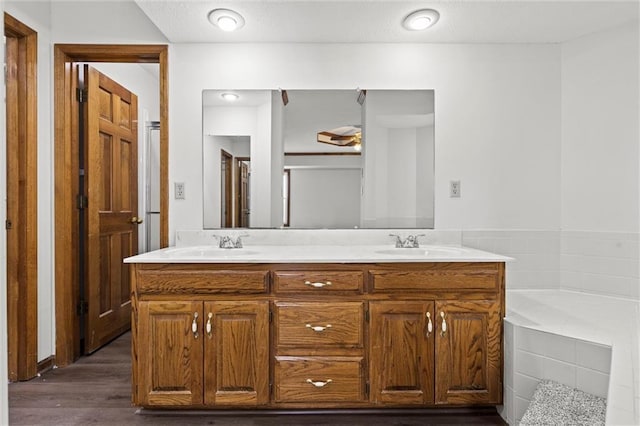 bathroom featuring tiled bath, vanity, and hardwood / wood-style flooring