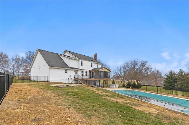 back of house featuring a sunroom, a patio area, a yard, and a covered pool