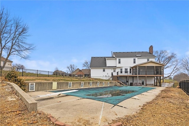 view of swimming pool featuring a diving board, a patio area, and a sunroom