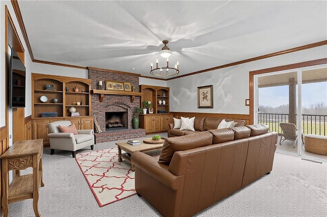 living area featuring built in features, wainscoting, ornamental molding, a fireplace, and a notable chandelier