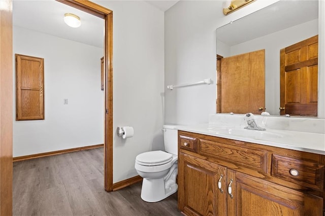 bathroom with toilet, baseboards, wood finished floors, and vanity