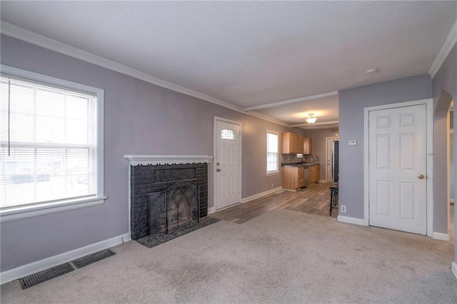 unfurnished living room with ornamental molding, light carpet, and a brick fireplace