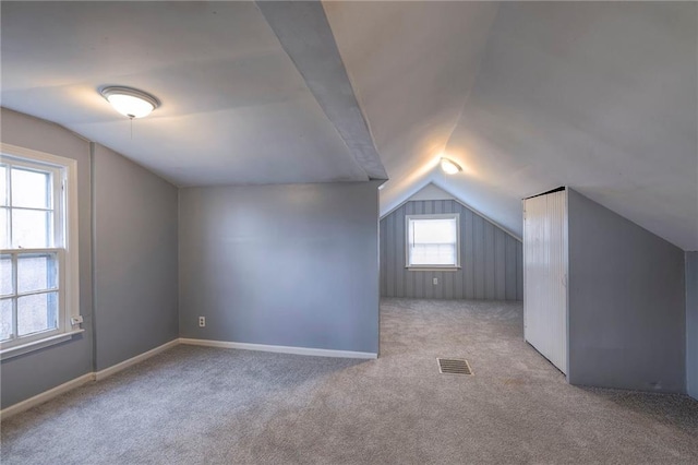 additional living space featuring lofted ceiling and light carpet