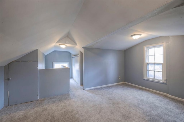 additional living space featuring light colored carpet and vaulted ceiling