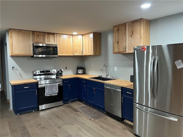 kitchen with hardwood / wood-style floors, appliances with stainless steel finishes, light brown cabinetry, and sink