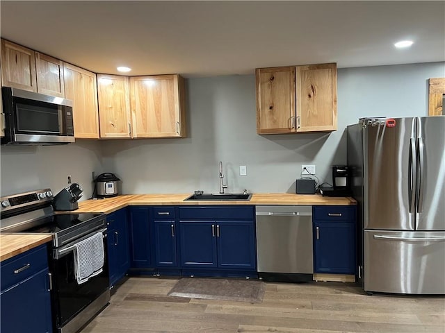 kitchen featuring wood counters, appliances with stainless steel finishes, blue cabinets, sink, and hardwood / wood-style floors