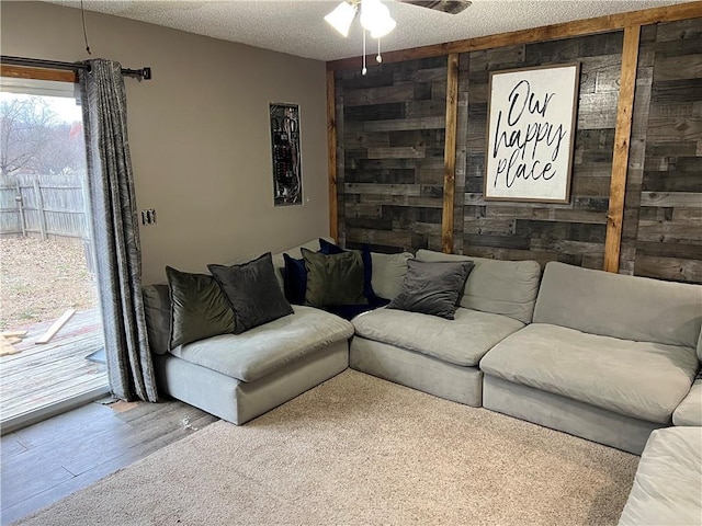 living room with hardwood / wood-style floors, a textured ceiling, ceiling fan, and wood walls