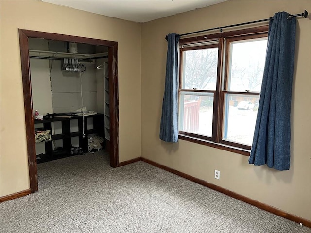 unfurnished bedroom with carpet flooring, a closet, and multiple windows