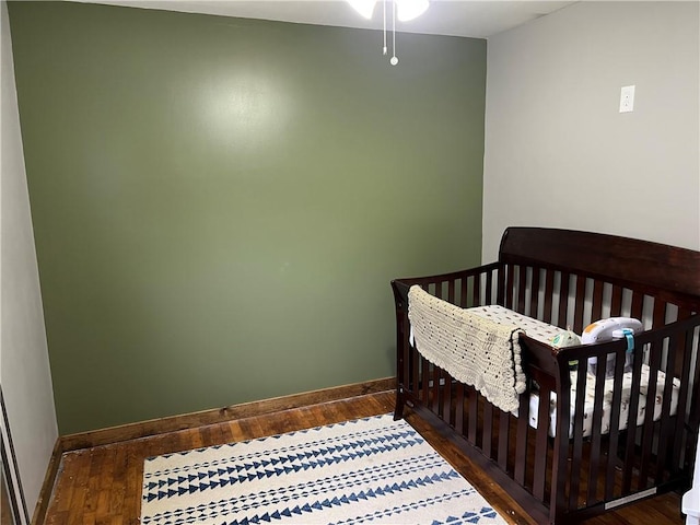 bedroom featuring dark hardwood / wood-style floors and a crib