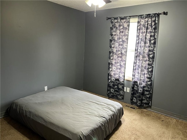 bedroom featuring carpet flooring, ceiling fan, and a textured ceiling