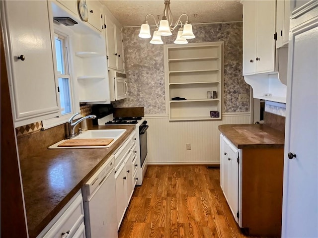 kitchen with white appliances, white cabinets, sink, pendant lighting, and wood counters