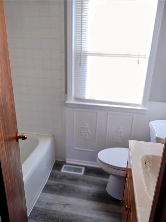 bathroom featuring hardwood / wood-style floors, a bathtub, toilet, and vanity