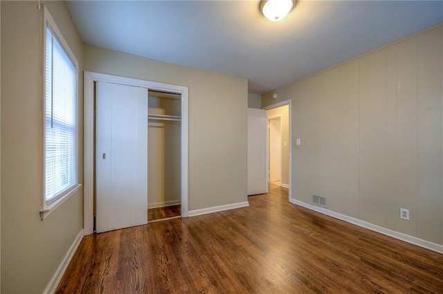 unfurnished bedroom featuring dark hardwood / wood-style flooring and a closet