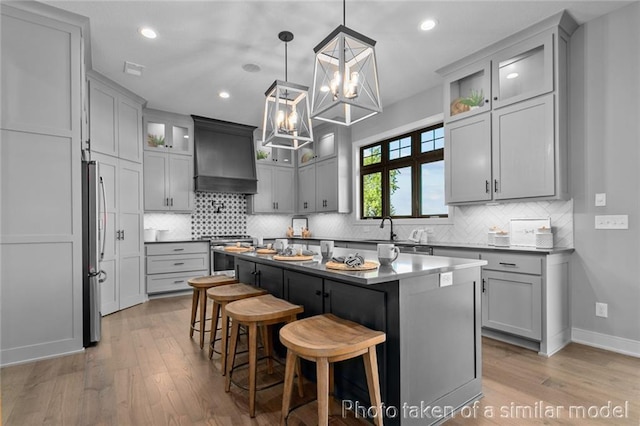 13450 W 179th Ter, Overland Park, KS 66013 - kitchen with light wood finished floors, stainless steel appliances, a chandelier, tasteful backsplash, and custom exhaust hood