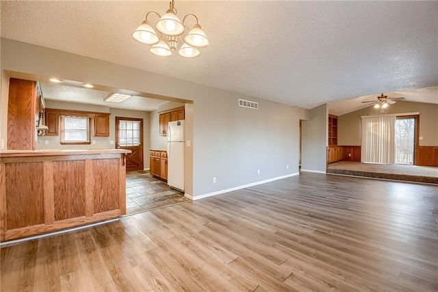 kitchen featuring white refrigerator, light hardwood / wood-style flooring, a wealth of natural light, and vaulted ceiling