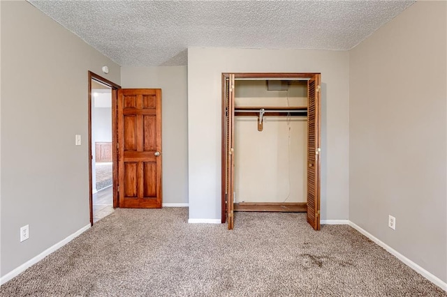 unfurnished bedroom featuring light colored carpet, a textured ceiling, and a closet