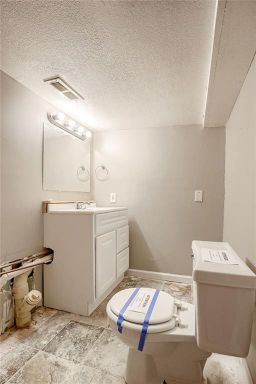 bathroom featuring vanity, toilet, and a textured ceiling