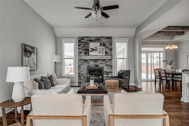 living area with dark wood-style floors, ceiling fan with notable chandelier, a fireplace, and baseboards