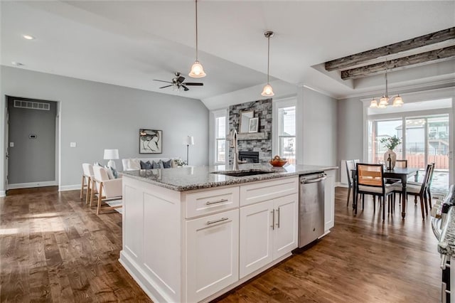 kitchen featuring light stone counters, a sink, white cabinets, hanging light fixtures, and stainless steel dishwasher