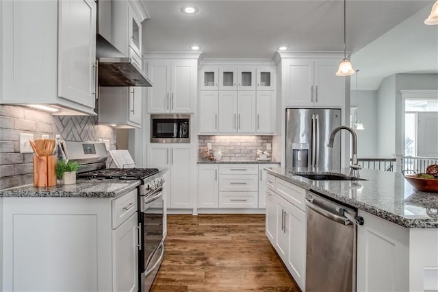 kitchen featuring stainless steel appliances, hanging light fixtures, glass insert cabinets, white cabinets, and wall chimney exhaust hood