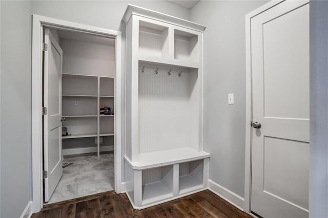 mudroom with dark wood finished floors and baseboards