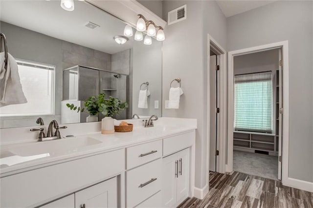 full bathroom featuring double vanity, a stall shower, visible vents, and a sink