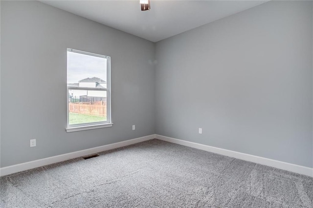 carpeted empty room featuring visible vents, ceiling fan, and baseboards