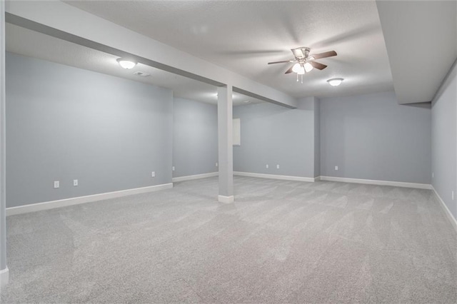 finished below grade area with a textured ceiling, baseboards, and light carpet