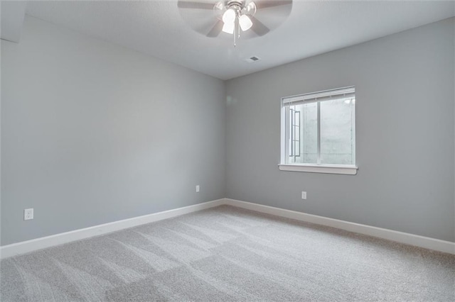 carpeted empty room featuring visible vents, a ceiling fan, and baseboards