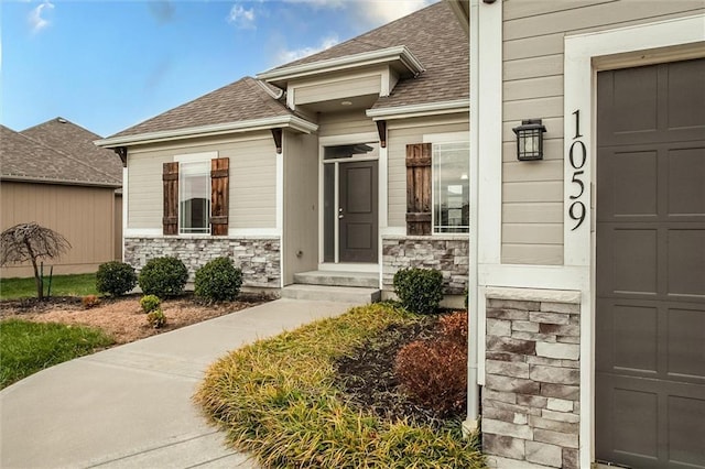 property entrance with an attached garage, stone siding, and roof with shingles