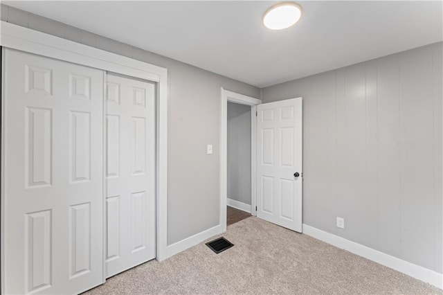 unfurnished bedroom featuring light colored carpet and a closet