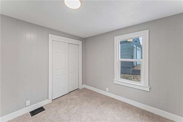 unfurnished bedroom featuring multiple windows, light carpet, and a closet