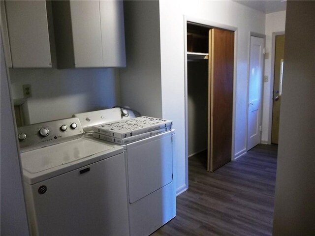 clothes washing area featuring cabinets, dark wood-type flooring, and washing machine and clothes dryer