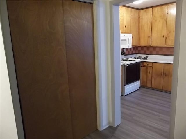 kitchen with decorative backsplash, light hardwood / wood-style floors, and white appliances