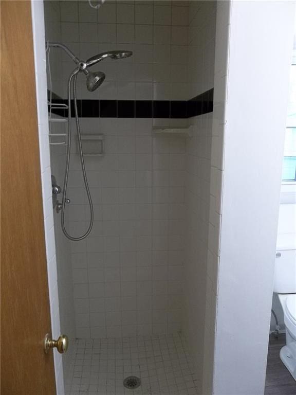 bathroom featuring tiled shower and toilet