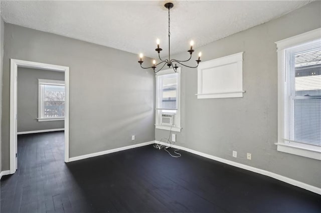 empty room with dark hardwood / wood-style floors, a chandelier, and a textured ceiling