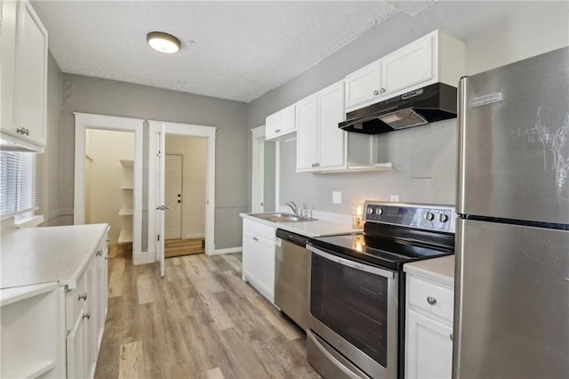 kitchen with sink, light hardwood / wood-style flooring, appliances with stainless steel finishes, a textured ceiling, and white cabinets